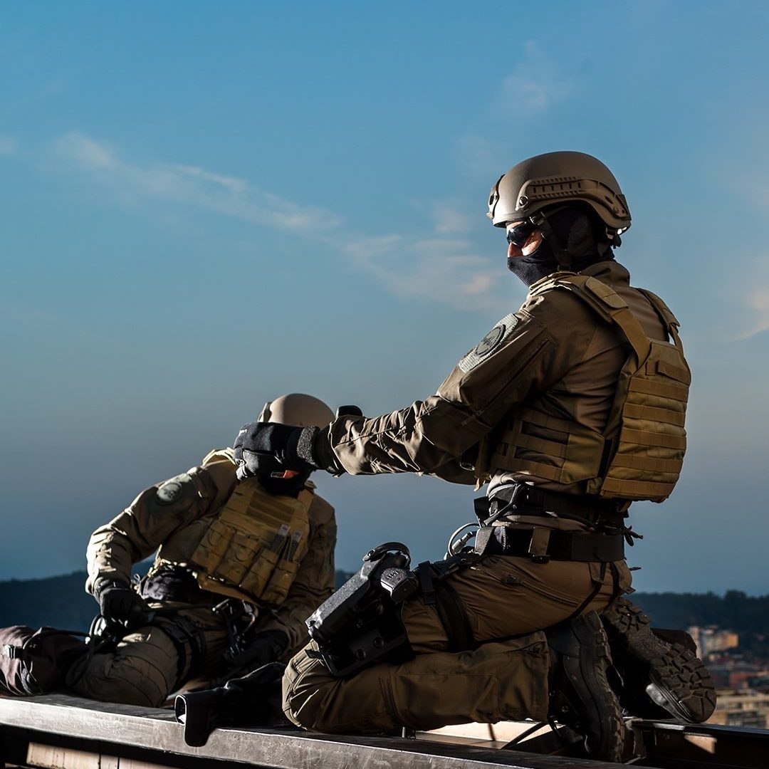 Two soldiers gearing up on a roof